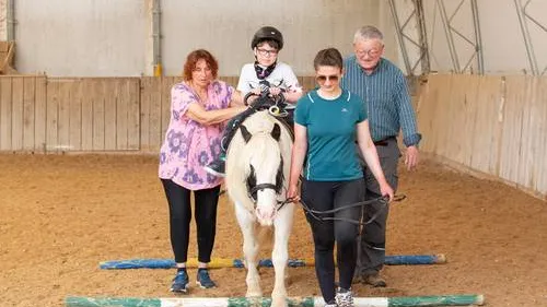 Vier Menschen mit Pferd in der Halle